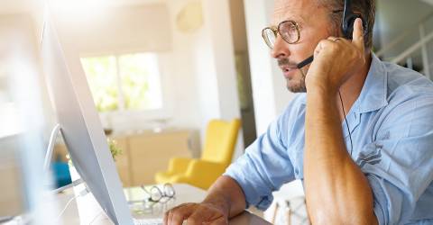 Zakenman werkt thuis zit achter zijn laptop en heeft een headset op